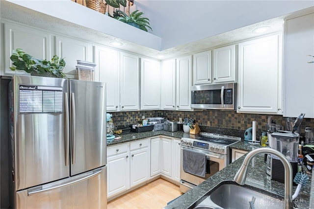 2540 Greenside Dr, Beavercreek, OH 45431 - kitchen featuring stainless steel appliances, white cabinets, dark stone counters, and backsplash