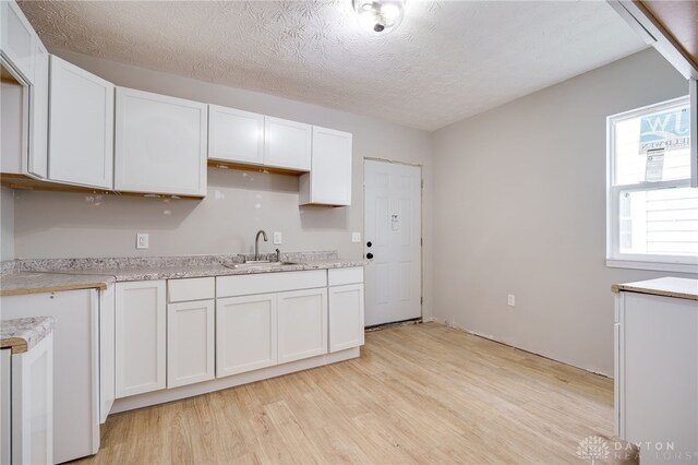 18241826 W Grand Ave, Dayton, OH 45402 - kitchen featuring a sink, light wood finished floors, white cabinets, light countertops, and a textured ceiling