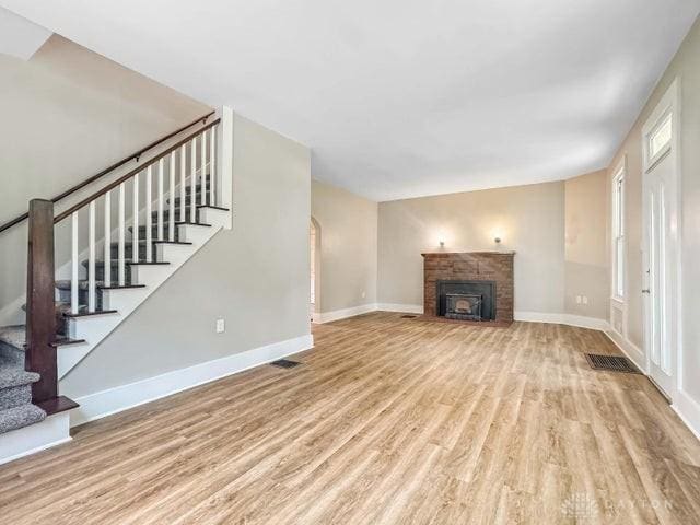244 Windsor Ave, Urbana, OH 43078 - unfurnished living room featuring wood finished floors, stairway, baseboards, and a fireplace with flush hearth