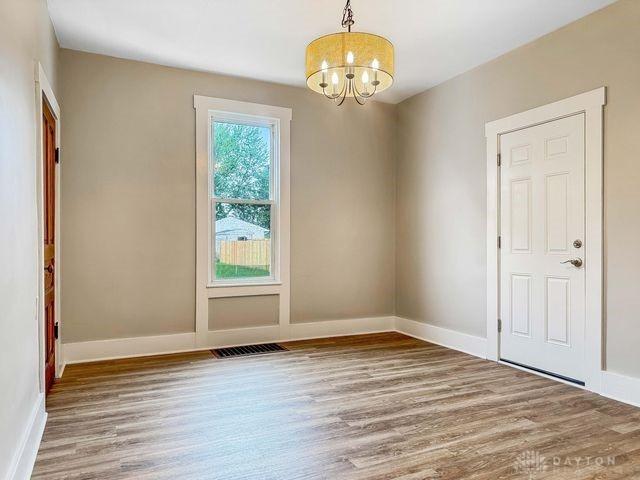 244 Windsor Ave, Urbana, OH 43078 - empty room featuring a chandelier, wood finished floors, and baseboards