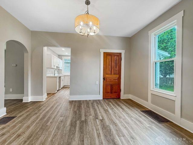 244 Windsor Ave, Urbana, OH 43078 - unfurnished dining area featuring light wood-style flooring, baseboards, a chandelier, arched walkways, and plenty of natural light