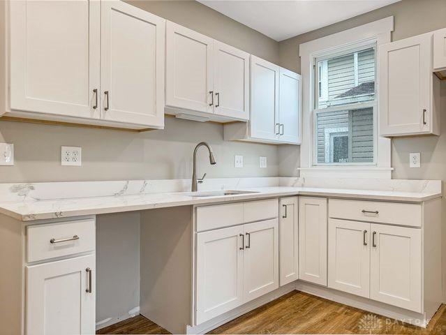 244 Windsor Ave, Urbana, OH 43078 - kitchen featuring a sink, white cabinetry, dark wood-style flooring, and light stone countertops