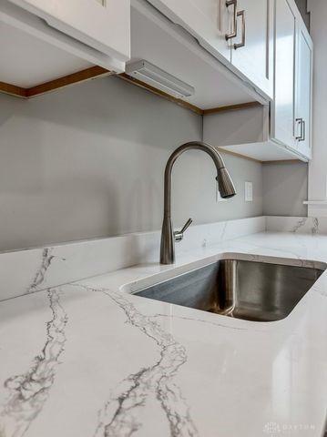 244 Windsor Ave, Urbana, OH 43078 - kitchen view of a sink, white cabinetry, and light stone counters