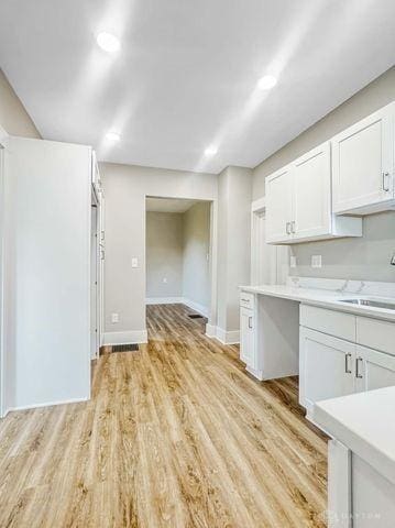 244 Windsor Ave, Urbana, OH 43078 - kitchen featuring a sink, light countertops, white cabinetry, light wood-style floors, and baseboards