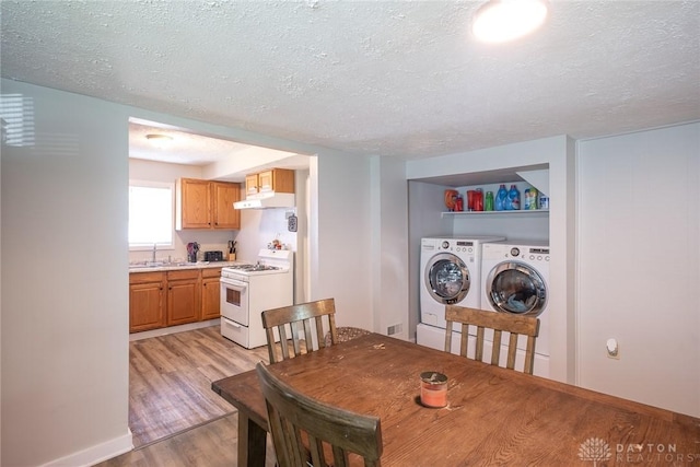 dining area with light wood finished floors, washer and dryer, a textured ceiling, and baseboards