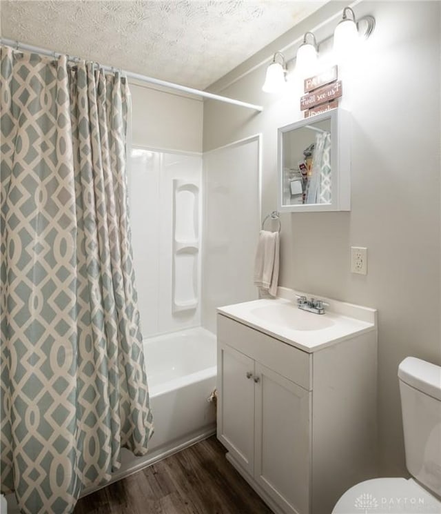 bathroom with a textured ceiling, toilet, wood finished floors, vanity, and shower / bath combo