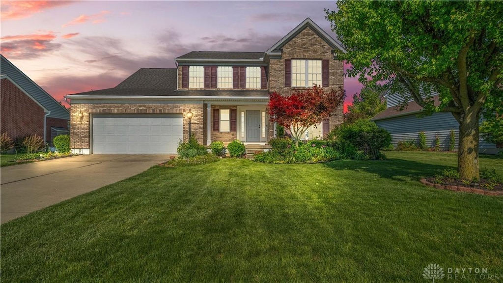 traditional-style house with an attached garage, driveway, a yard, and brick siding