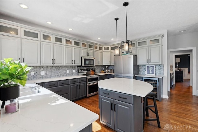 kitchen featuring gray cabinetry, appliances with stainless steel finishes, wine cooler, a center island, and tasteful backsplash