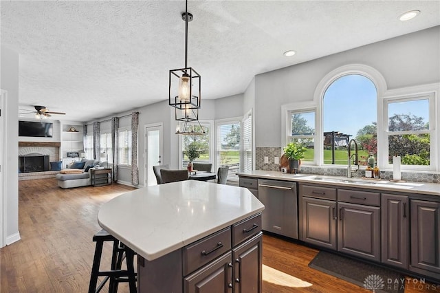 kitchen featuring dishwasher, a ceiling fan, a sink, dark wood finished floors, and a textured ceiling