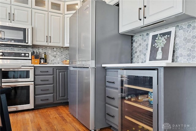 kitchen featuring stainless steel appliances, wine cooler, gray cabinets, and decorative backsplash
