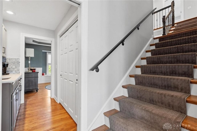 stairs with wood finished floors and recessed lighting