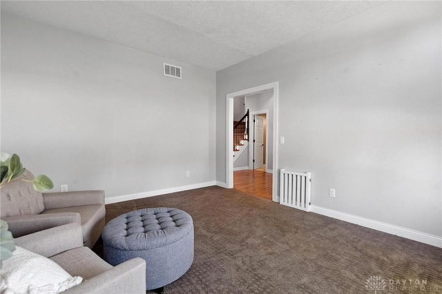 carpeted living room featuring stairs, a textured ceiling, and baseboards