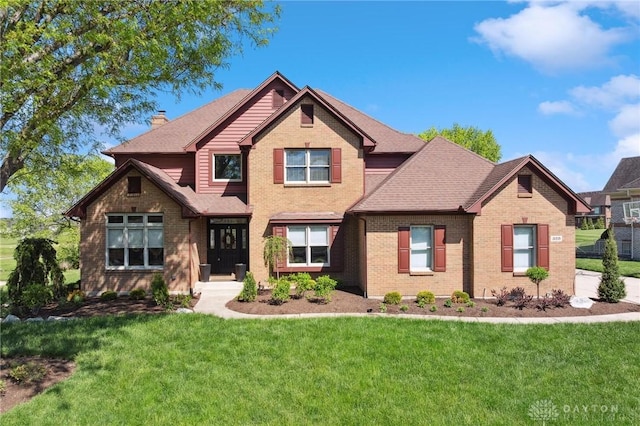 craftsman inspired home featuring brick siding, a front lawn, a chimney, and roof with shingles