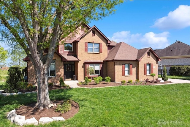 view of front of house featuring a front lawn, brick siding, and roof with shingles