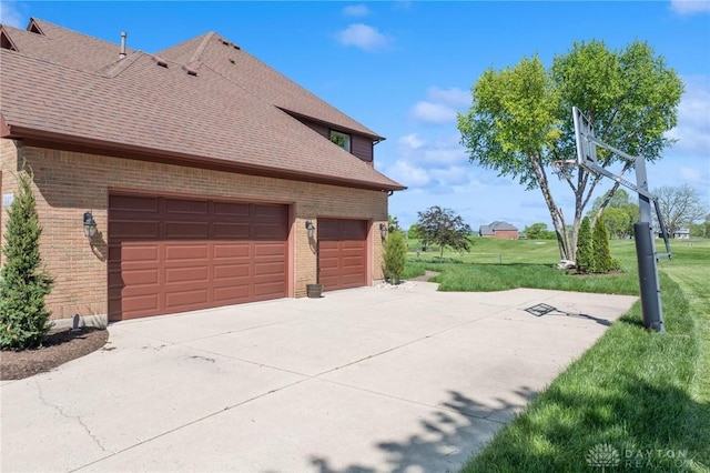 view of side of home featuring brick siding, a yard, a shingled roof, and an attached garage