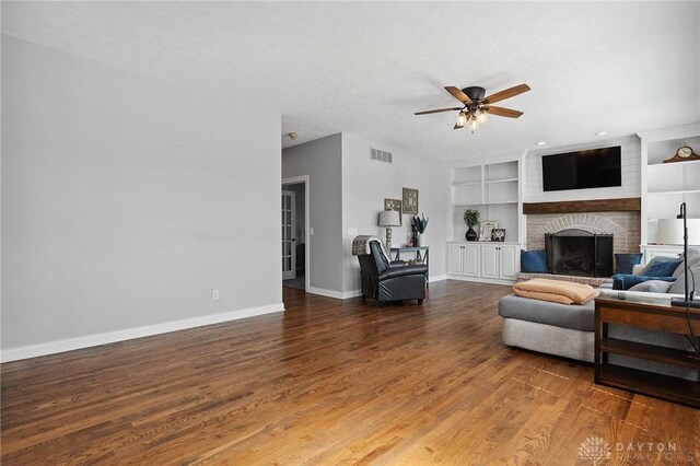 living area featuring a ceiling fan, baseboards, a brick fireplace, and built in features