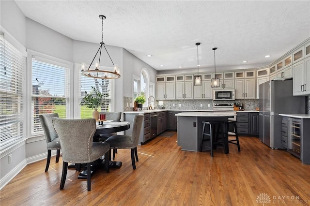 dining space featuring wine cooler, a chandelier, wood finished floors, a textured ceiling, and recessed lighting