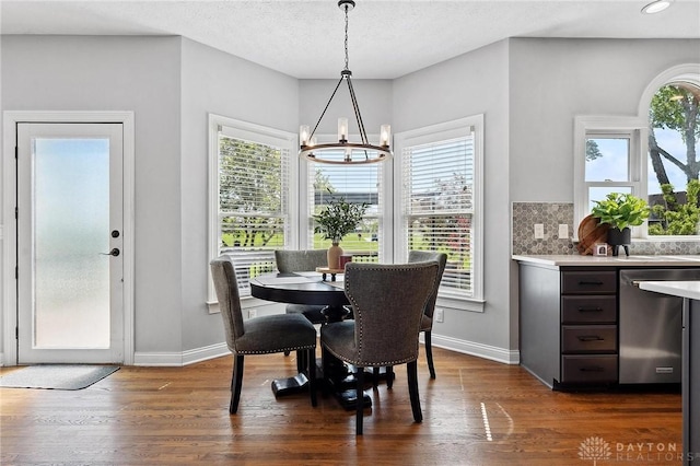 dining area featuring a chandelier, dark wood finished floors, and baseboards