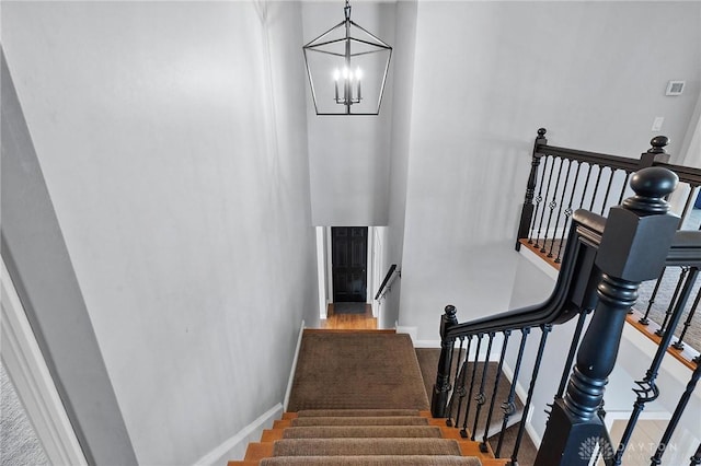 stairway featuring baseboards and a chandelier