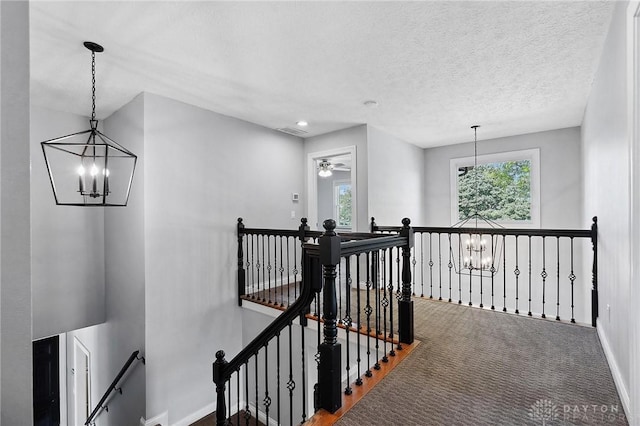 hall featuring an upstairs landing, a chandelier, baseboards, and carpet floors