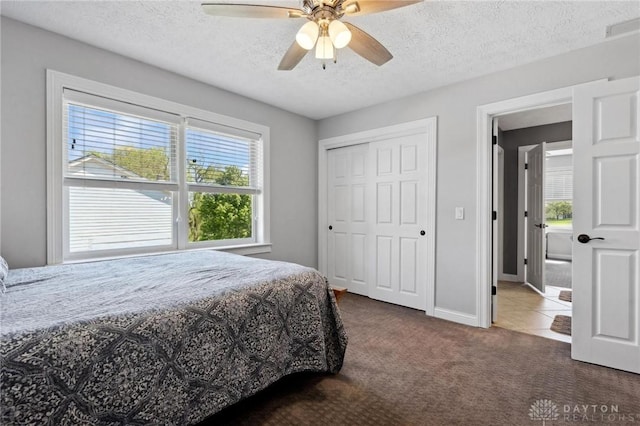 bedroom featuring carpet flooring, a textured ceiling, baseboards, a closet, and ceiling fan