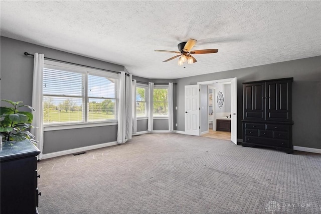 unfurnished bedroom featuring baseboards, carpet, a textured ceiling, ceiling fan, and connected bathroom