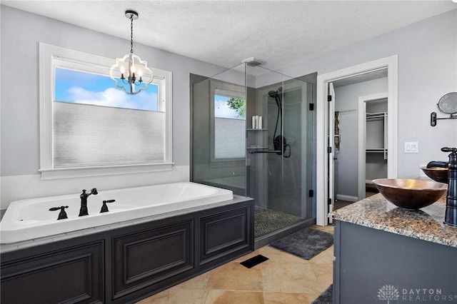 full bath with a stall shower, a chandelier, a walk in closet, a garden tub, and a textured ceiling