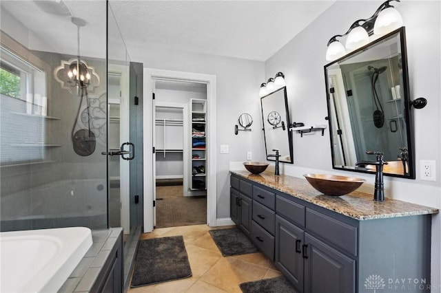 bathroom with a shower stall, a chandelier, double vanity, a walk in closet, and tile patterned floors