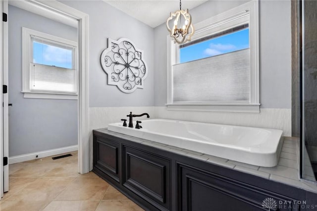 full bath featuring a chandelier, a bathtub, and tile patterned flooring