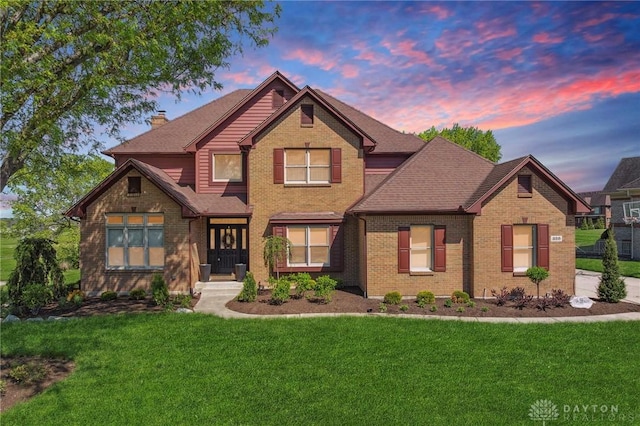 craftsman-style home with a front yard, brick siding, a chimney, and a shingled roof