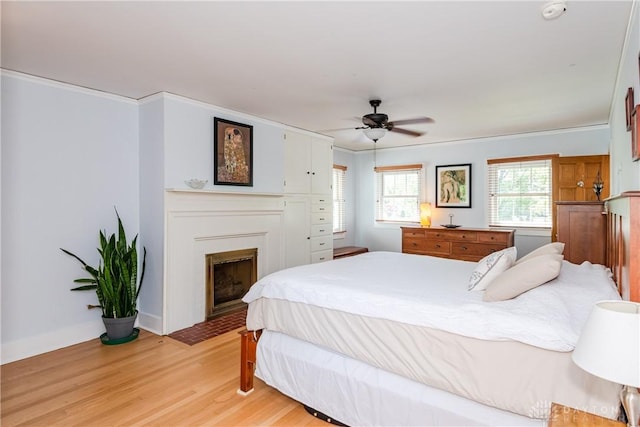 135 E Dixon Ave, Oakwood, OH 45419 - bedroom featuring crown molding, light wood finished floors, a fireplace with flush hearth, a ceiling fan, and baseboards