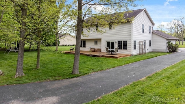 rear view of house featuring a wooden deck and a lawn