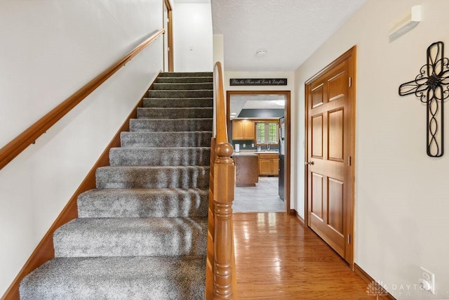 stairs featuring wood finished floors and a textured ceiling