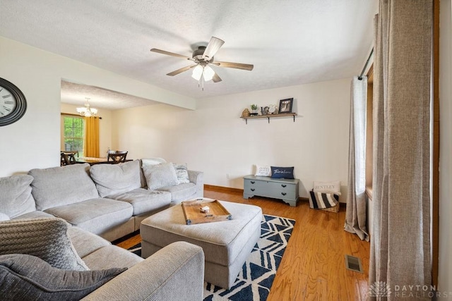 living room featuring a chandelier, light wood finished floors, and ceiling fan