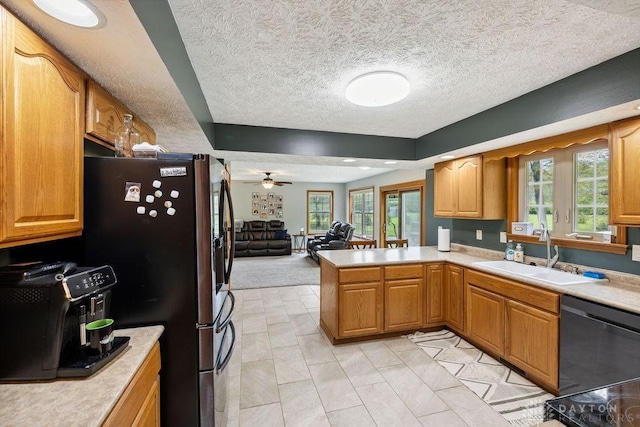 kitchen featuring dishwashing machine, a sink, open floor plan, a textured ceiling, and light countertops