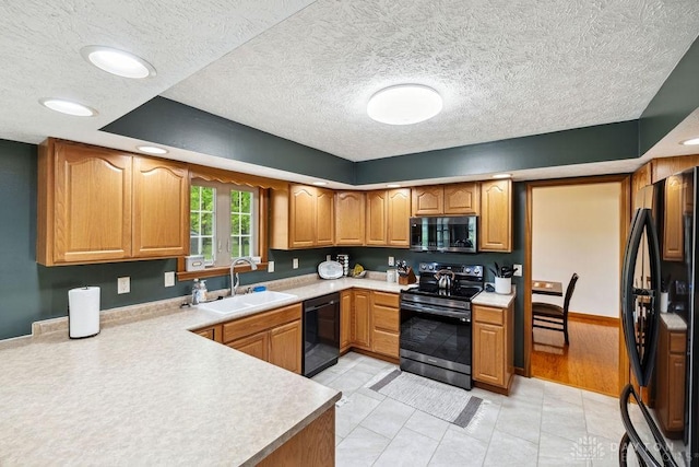 kitchen featuring black appliances, a sink, light countertops, a textured ceiling, and brown cabinetry