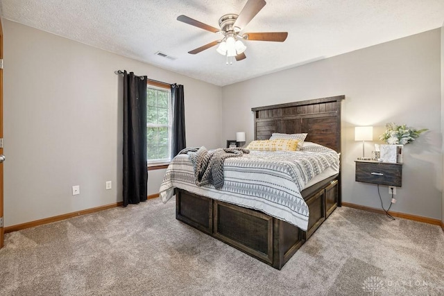 bedroom featuring light carpet, baseboards, a ceiling fan, and a textured ceiling
