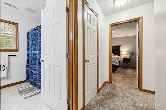 hall featuring a textured ceiling and baseboards