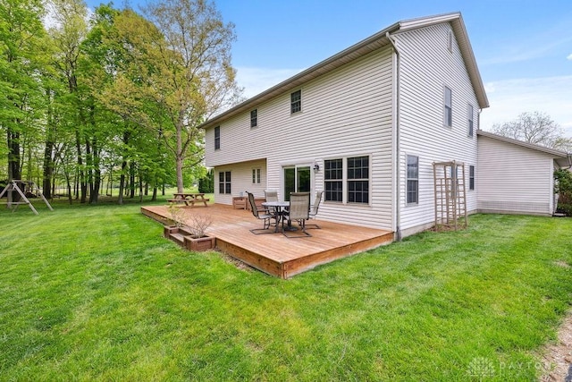 rear view of house featuring a wooden deck, outdoor dining space, and a yard