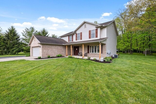 view of front facade with driveway, a garage, brick siding, a front yard, and covered porch