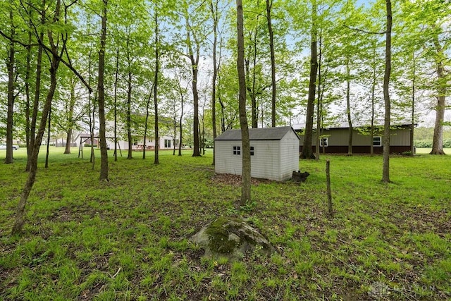 view of green lawn with an outbuilding and a storage shed