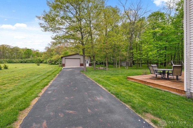 view of grassy yard with an outbuilding, a garage, a deck, and outdoor dining area