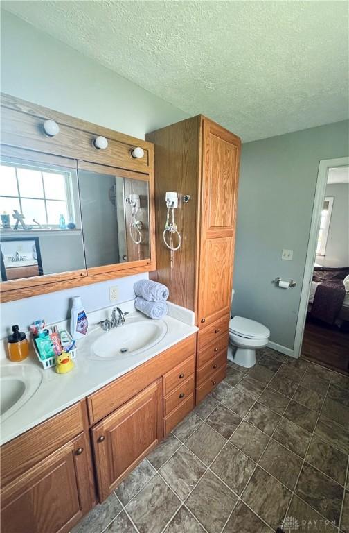 bathroom featuring a textured ceiling, double vanity, and toilet