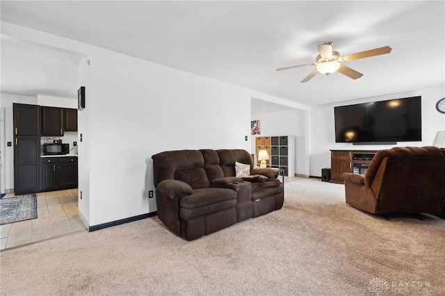 living area with ceiling fan, light colored carpet, and baseboards