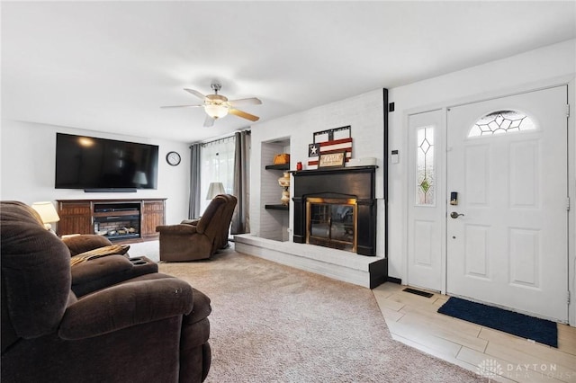living room featuring a fireplace, a ceiling fan, light carpet, and light tile patterned floors