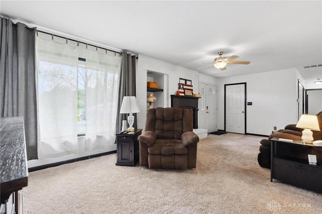 living area featuring carpet flooring, a ceiling fan, and baseboards
