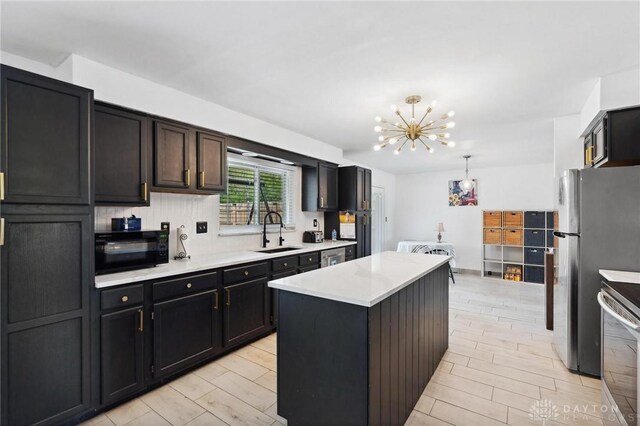 kitchen with a sink, stainless steel appliances, a chandelier, light countertops, and a center island