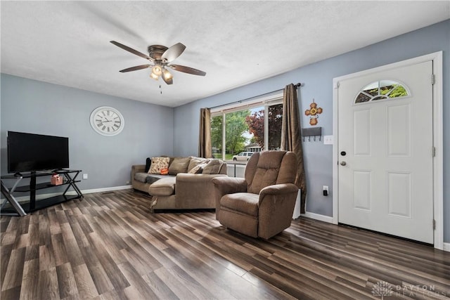 living area with dark wood finished floors, a ceiling fan, and baseboards