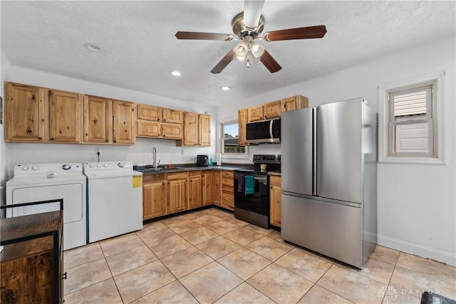 kitchen featuring stainless steel appliances, independent washer and dryer, a sink, light tile patterned flooring, and a ceiling fan