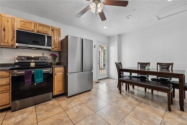 kitchen featuring stainless steel appliances, dark countertops, a textured ceiling, light tile patterned floors, and a ceiling fan